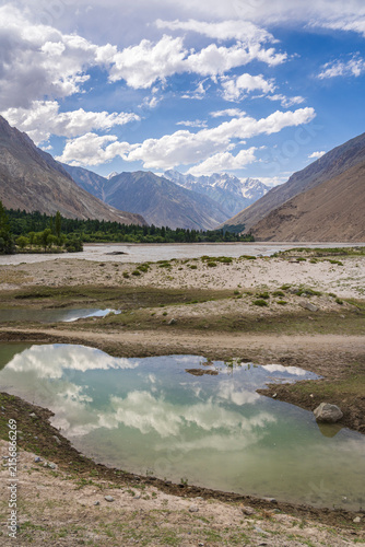 Scenic vertical landscape view of Shigar river valley with sky reflection in water, Shigar, Gilgit Baltistan, Pakistan