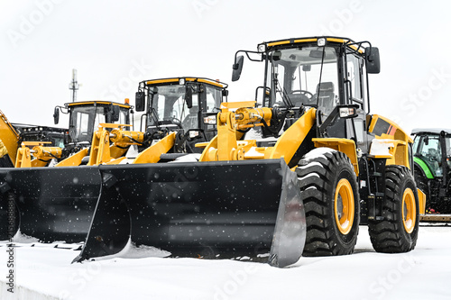 Front-end loaders and other construction machinery parked at an equipment yard. Heavy equipment ready for use in construction, earthmoving, roadwork, and infrastructure projects.