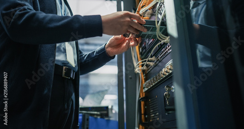 Obraz na płótnie Low Angle View of Male Engineer Hands Connecting Fiber Optic Cable Into Server Rack Patch Panel, Performing Network Infrastructure Setup and Hardware Repair in Modern AI Data Center Facility