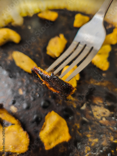 Close-up of Burnt Food on Fork from Greasy Cooking Surface
