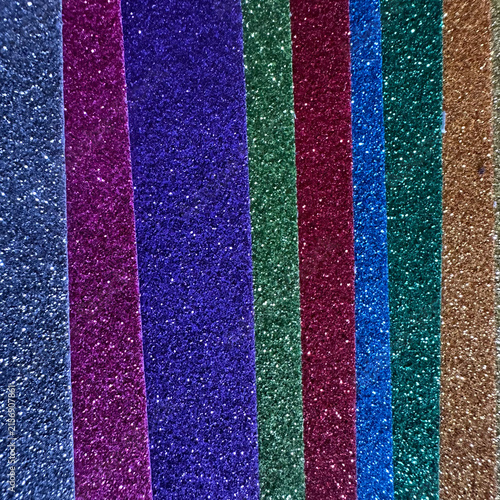 Vertical strips of multi-colored glitter paper, textured background