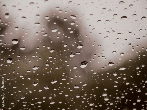 Quadro su tela Raindrops clinging to a clear glass window during a heavy downpour with soft blu