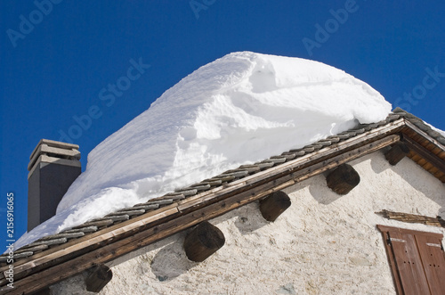 snow covered roof of an old mountain house in the Italian Alps