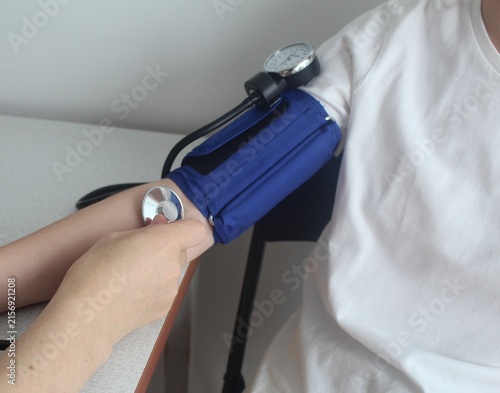 Doctor applying a blood pressure cuff and a stethoscope for a check-up.