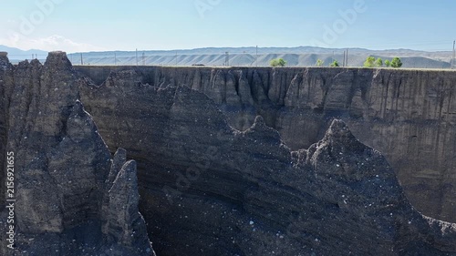 Aerial view of jagged mudstone formations and steep canyon walls under a clear blue sky in Anjihai Grand Canyon, Xinjiang, China