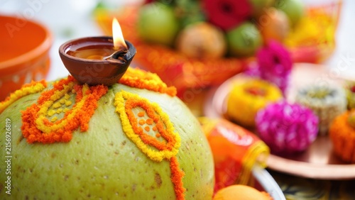 Decorated coconut offering topped with a glowing diya during chhath puja worship, sun god worship ritual, traditional arghya offering, bihar hindu celebration, devotional family observance