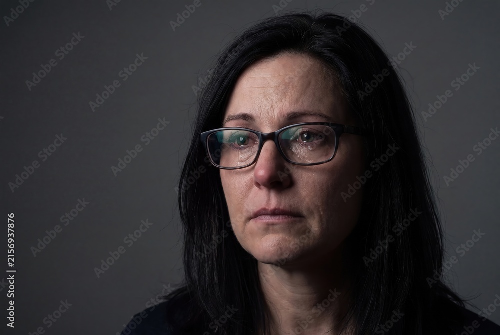 Fototapeta premium Depressed middle aged woman crying with glasses emotional portrait