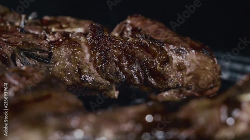 Close up of juicy seasoned steak sizzling on grill with rosemary and char marks