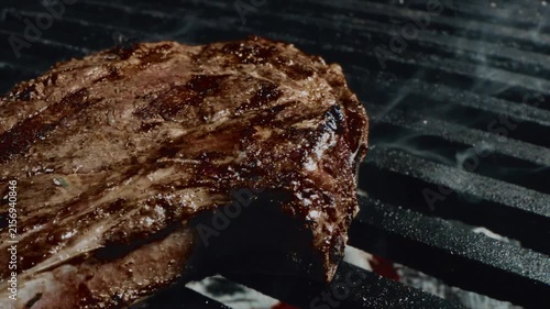 Close up of juicy steak sizzling on a grill with charred marks and smoky juices