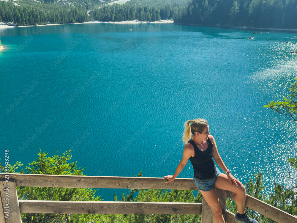 Obraz premium Hiking, excited and woman on mountain with lake for adventure, trekking and freedom. Travel, nature and happy person outdoors for wellness, walking and exercise on holiday, journey and vacation