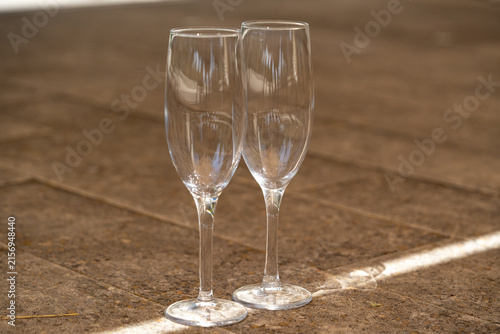 Obraz na plátne Two empty crystal champagne flutes standing on a textured stone surface