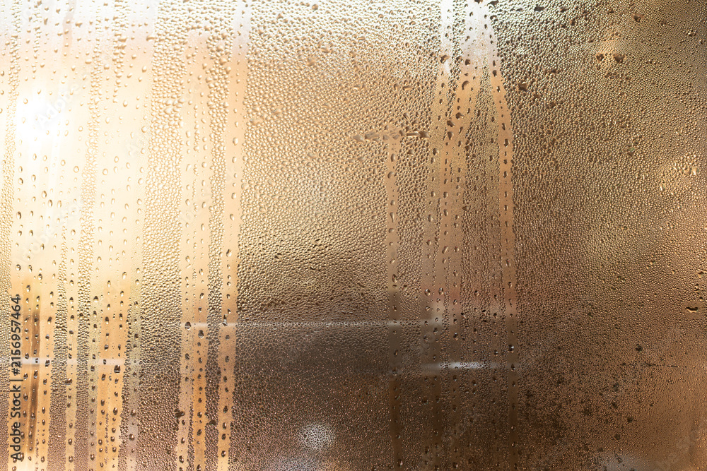 Naklejka premium Condensation glass window droplet moisture texture abstract condensation covered glass window with water droplet texture and warm light creating private, atmospheric surface for background design