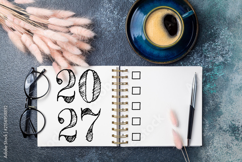 New year resolutions 2027 on desk. 2027 goals list with notebook, coffee cup, plant on table. Resolutions, plan, goals, action, checklist, idea concept. New Year 2027 resolutions, copy space