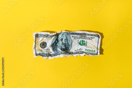 Crumpled hundred dollar bill on yellow background