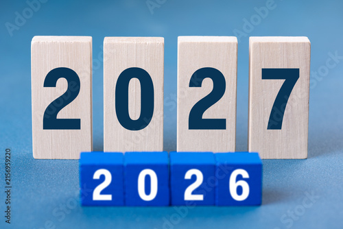 2027 Happy New Year. Wooden cube block change from 2026 to 2027 on blue. Concept 2027 New Year background. Business, resolutions, goals, inspiration, success, ideas