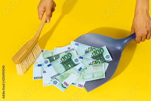 Hands sweeping hundred dollar bills with broom