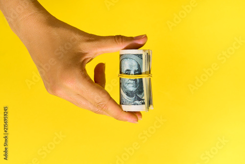  Hand holding roll of hundred dollar bills