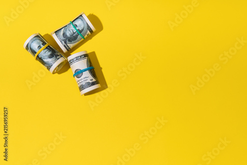  Rolls of hundred dollar bills on yellow background
