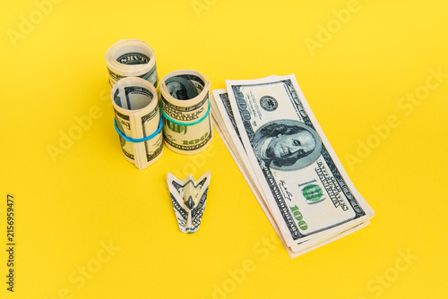 Money airplane with hundred dollar bills on yellow background