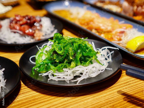 Delicious seasoned green seaweed salad served as an authentic Japanese appetizer on a black ceramic dish
