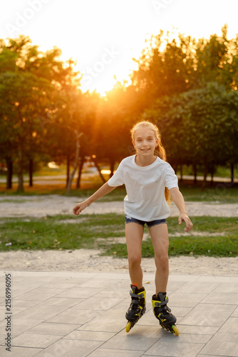 Canvastavla A lovely fair-haired girl is skating on yellow roller skates in the golden hour