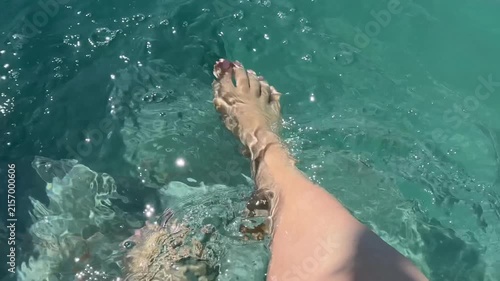 A pair of bare feet wading in crystal clear turquoise tropical ocean water, suggesting relaxation and vacation moments, perfect for travel content