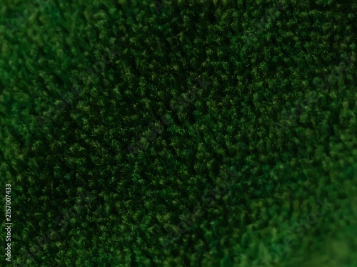 Close up macro shot of deep green fuzzy textured fabric with visible fibers and soft lighting