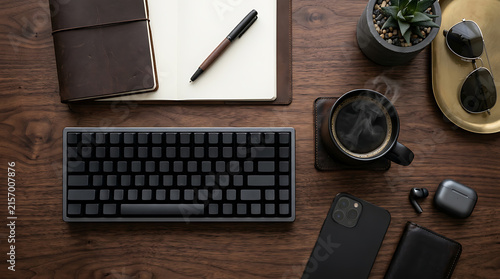 Modern workspace setup with keyboard, notebook, and coffee on a wooden desk