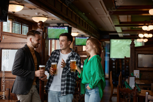 Foto Group of friends toasting with craft beers in warm wooden pub interior