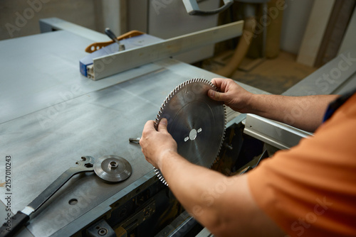 Expert technician precisely aligning saw teeth on metal blade while ensuring safety measures