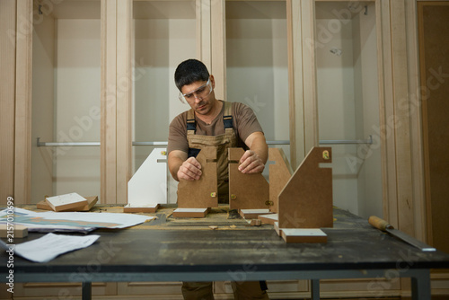 Diligent worker carefully positioning and measuring components for personalized furniture creation