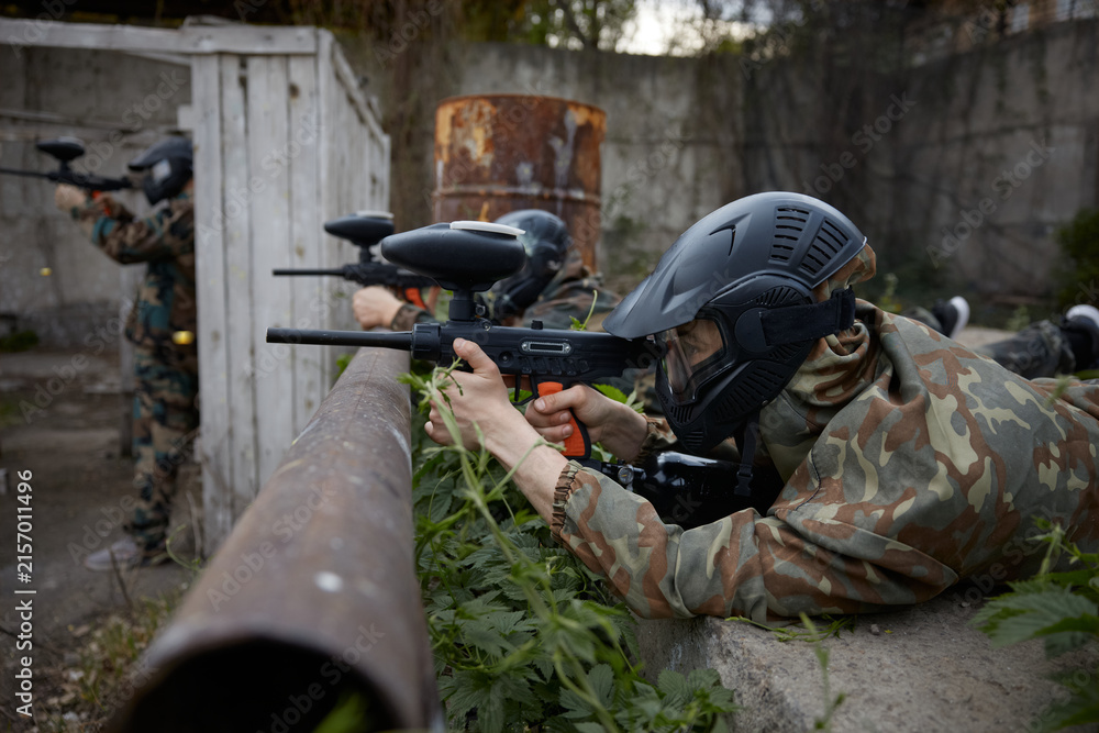 Naklejka premium Portrait of a soldier aims a gun while leaning on a pipe, lying on the ground