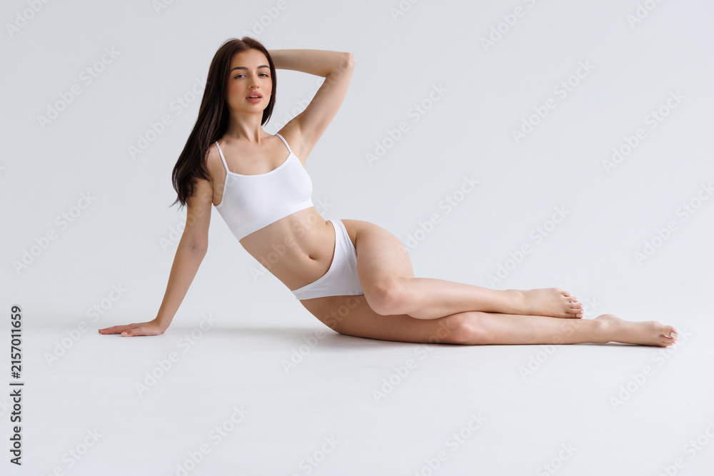 Fototapeta premium Beautiful woman with perfect body lying on white background