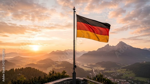 German flag waving proudly against a dramatic sunset mountain landscape