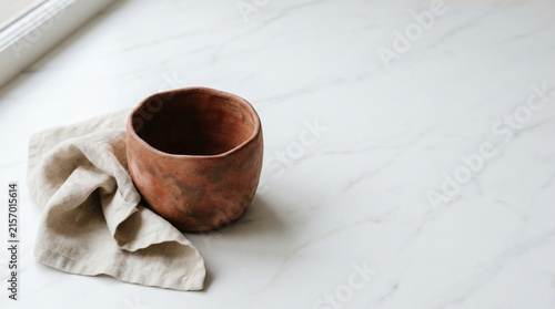 Rustic clay bowl and linen cloth on white marble, minimalist high-key shot, perfect for pottery branding, interior blogs and kitchenware ads.
