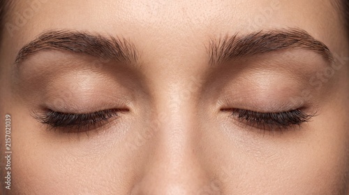 Natural beauty close up featuring soft skin texture and defined brows with closed eyelids with gently closed
