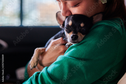 Woman tenderly embraces her beloved chihuahua dog in car