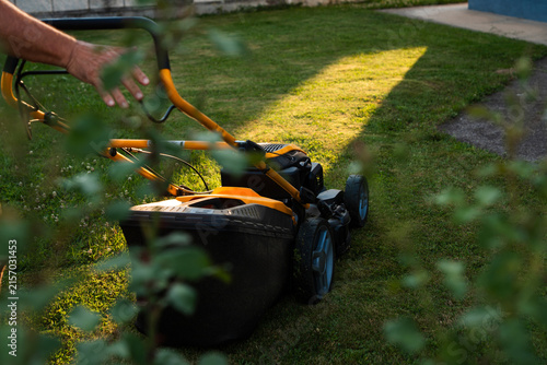 Close up of lawn mower collecting grass during evening yard work