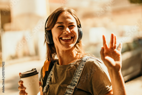 Young woman enjoying music and coffee on city street