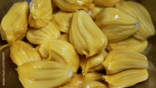 Close up of ripe jackfruit pods with glossy yellow flesh piled together, showing fresh tropical fruit texture and natural sweetness.