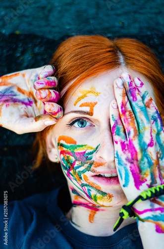 Artistic woman portrait with colorful paint on face and hands