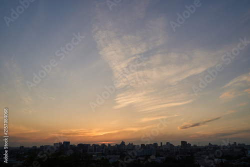 Canvas Print City Skyline Silhouetted Beneath Warm Sunset Clouds Over Wide Urban Horizon