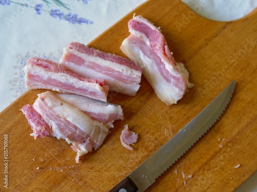 Raw Sliced Pork Belly and Thick Bacon on a Wooden Cutting Board with Knife