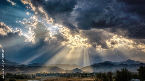 Dramatic sun rays breaking through heavy clouds over distant mountains