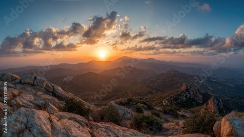 Golden sunrise illuminating rugged mountain peaks over vast rolling