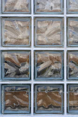 фотографія A vertical full frame background texture showing a grid pattern of translucent square glass blocks with wavy internal patterns in a white wall