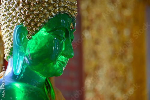 Close Up of Emerald Green Buddha Face with Golden Bokeh and Copy Space