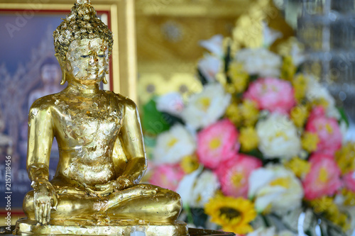 Golden Buddha Statue Covered with Gold Leaf and Flowers in Thai Temple