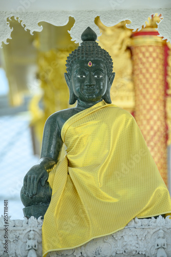 Dark Buddha Statue Draped in Golden Robe Inside Thai Buddhist Temple