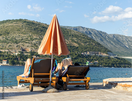 Cuadro en lienzo People relax on sun loungers by the water in Dubrovnik, Croatia during a summer